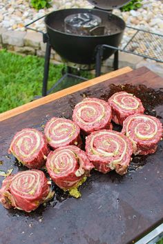 some food is laying out on a grill with grass and rocks in the back ground