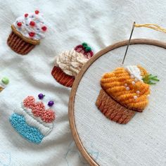 some cupcakes are on the table and one is stitched in to a hoop