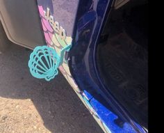 the tail end of a car that has been painted blue and pink with an image of a shell on it