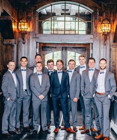 a group of men standing next to each other in front of a door wearing suits