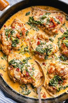 a skillet filled with chicken and spinach covered in cheese