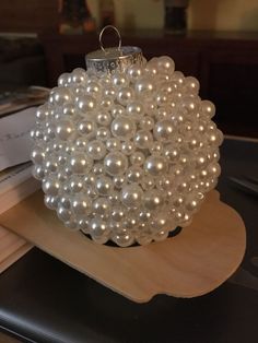 a white beaded ornament sitting on top of a wooden tray next to papers