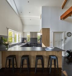 a kitchen with three bar stools next to an island in the middle of it