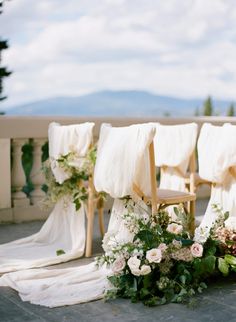 the chairs are lined up with flowers and greenery