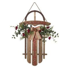 a wooden sled decorated with holly and red berries is hanging on the wall in front of a white background