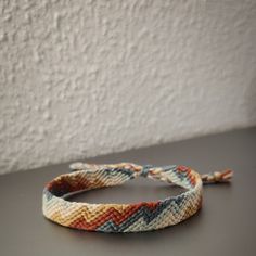 a braided bracelet sitting on top of a black table next to a white wall