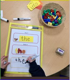 a person is writing on a piece of paper with letters and numbers in front of them