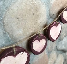 three heart shaped wooden ornaments hanging on a rope next to some rocks and paper hearts