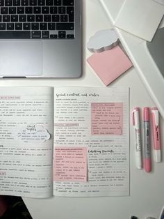 an open notebook sitting on top of a white desk next to a laptop and pen