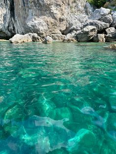 the water is crystal clear and blue with some rocks in the backgrouds