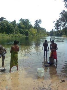 some people are standing in the water and one is holding a bucket