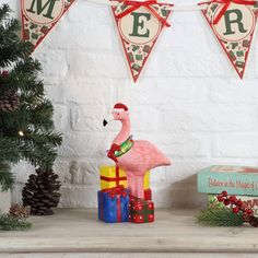 a pink flamingo statue sitting on top of a wooden table next to christmas presents