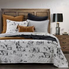 the bed is made with black and white animals on it, along with brown pillows