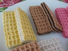 four crocheted pieces of bread on a white plate with pink and yellow flowers