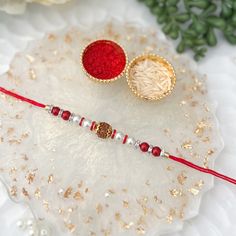 two red and white beaded bracelets sitting on top of a glass plate