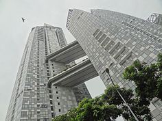 the tall building has many windows on it's sides and is surrounded by trees