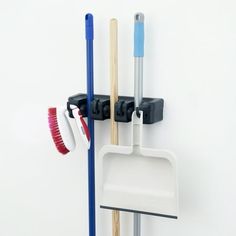 two brooms are hanging on the wall next to a toothbrush holder and cleaning brush