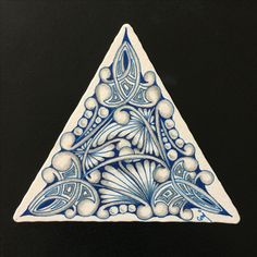 a blue and white triangle shaped object on a black surface with an intricate design in the center