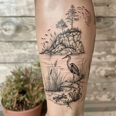 a person's leg with a bird and water scene tattoo on it, next to a potted plant