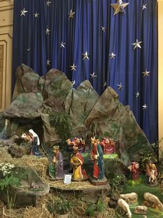 the nativity scene is displayed in front of a blue curtain with stars on it