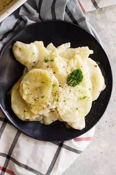 a black plate topped with ravioli and parsley