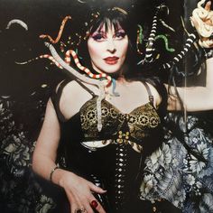 a woman in a corset and snake headdress with her hands on her hips