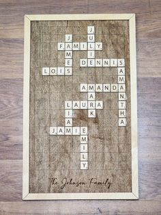 a wooden crossword puzzle with the names of family and friends written in white on it