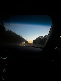 the sun is setting in the distance as seen from inside a car's dashboard