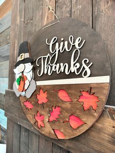 a wooden sign that says give thanks with a turkey holding a pumpkin in it's hand