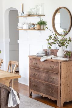 a wooden dresser sitting on top of a hard wood floor next to a table and chairs