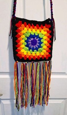 a crocheted bag hanging on a door handle with multicolored yarns