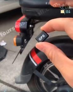 a hand holding a gps device in front of a scooter