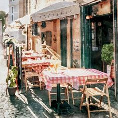 an outdoor dining area with tables and chairs on the sidewalk in front of a building