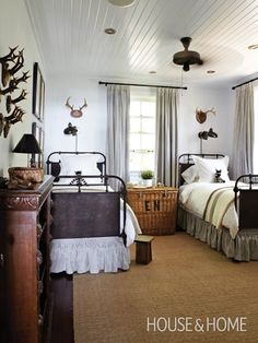 two twin beds in a bedroom with antlers on the wall and curtains over them