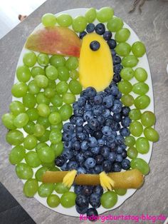 a plate topped with grapes and blueberries next to a bird made out of fruit