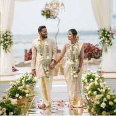 a man and woman standing next to each other in front of an arch with flowers on it