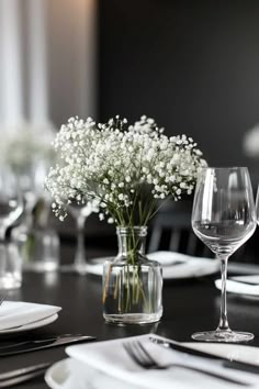 the table is set with white flowers and wine glasses, silverware and napkins