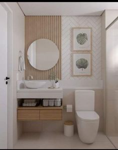 a white toilet sitting next to a bathroom sink under a round mirror on a wall