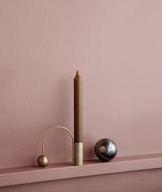 a candle is sitting on top of a shelf next to a ball and a stick