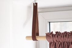 a brown curtain is hanging from a hook on a white door with a window in the background