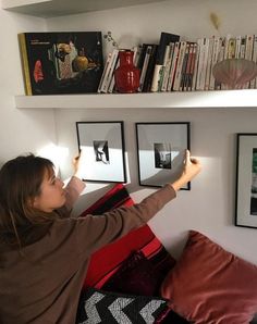 a woman is hanging pictures on the wall