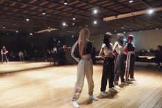 a group of young people standing on top of a wooden floor next to each other