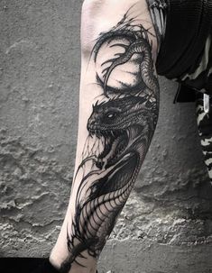 a man's arm with a black and white dragon tattoo on the left forearm