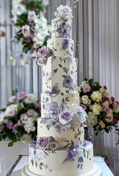 a three tiered cake with purple and white flowers