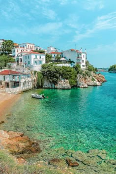 a small boat is in the clear blue water near some houses and beachfronts