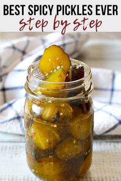 a jar filled with pickles sitting on top of a white table cloth next to a blue and white towel