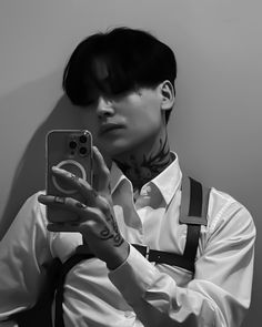 a man with tattoos taking a selfie in front of a mirror while wearing suspenders