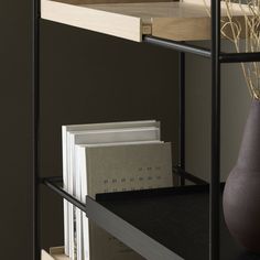 a book shelf with books and a vase on the top, against a dark wall