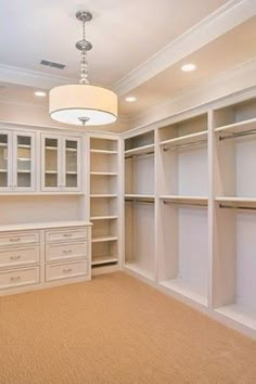 an empty walk in closet with lots of white shelves and drawers on either side of the closet