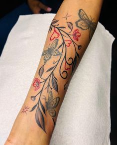 a woman's arm with flowers and butterflies tattooed on the left side of her arm